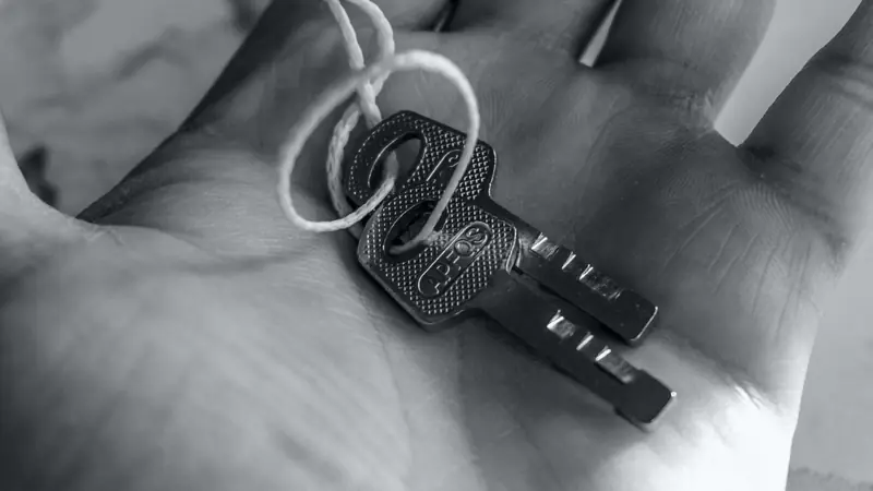 Deux clés reliées par une cordelette posées dans la paume d'une main, en noir et blanc