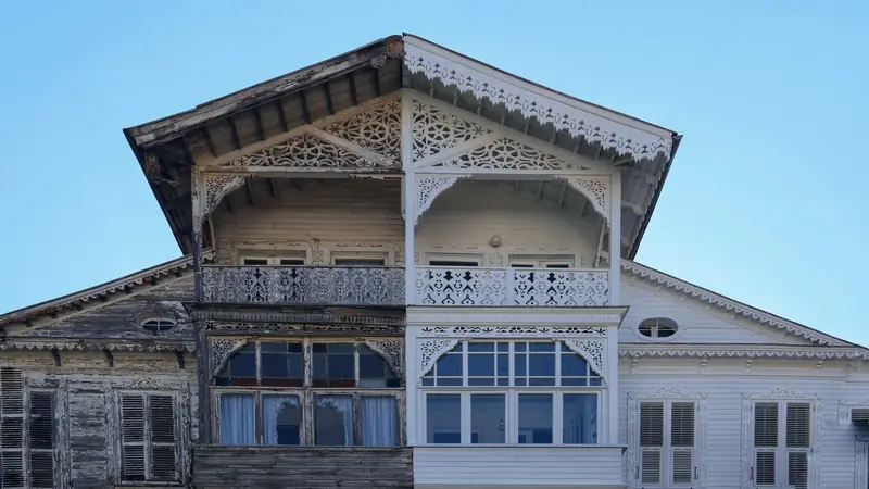 Façade d'une maison en bois dont une moitié est rénovée en blanc et l'autre encore usée