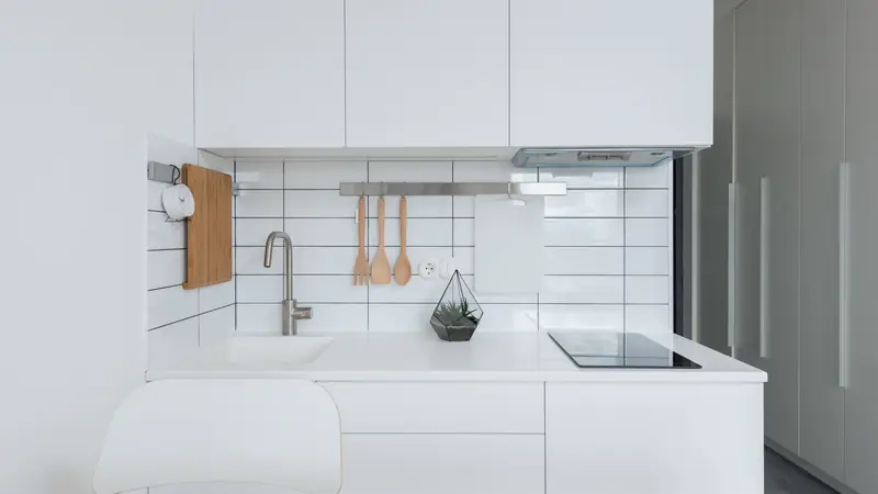 Cuisine équipée avec plaques de cuisson, four et ustensiles dans un petit appartement
