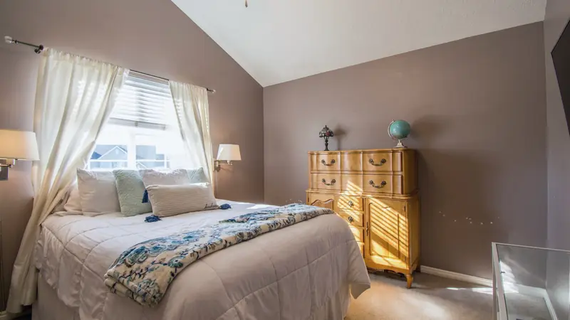 Chambre meublée avec un lit fait, une lampe de chevet et des rideaux occultants