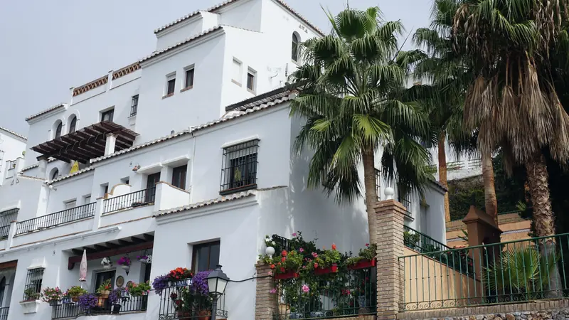 Maison blanche à balcons fleuris et ferronneries, entourée de palmiers, dans le sud de l'Espagne