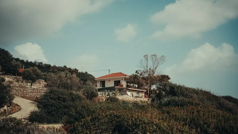 Villa ancienne aux façades claires entourée de végétation sur une colline au bord de la mer